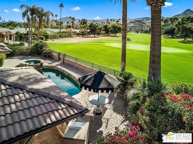 view of pool with a lawn, a mountain view, a patio, and an in ground hot tub