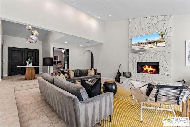 tiled living room featuring a stone fireplace