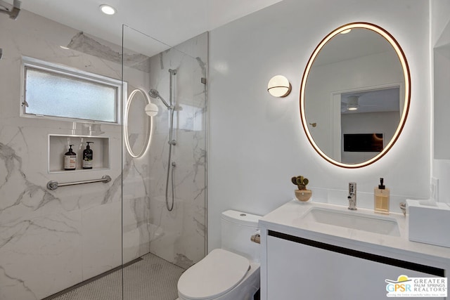 bathroom featuring a tile shower, vanity, and toilet