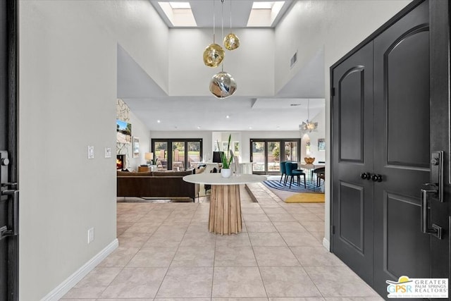 foyer featuring light tile patterned floors, high vaulted ceiling, and a skylight