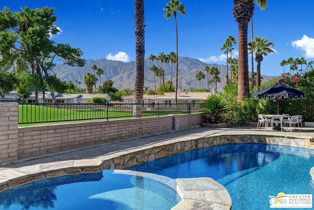 view of pool with a mountain view, a yard, and an in ground hot tub