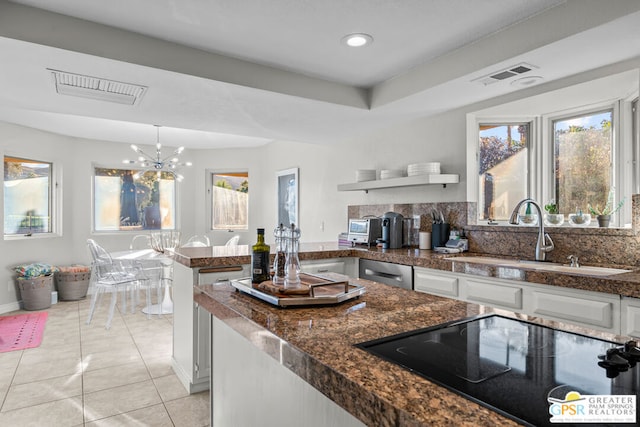 kitchen with black electric stovetop, white cabinets, sink, and a chandelier