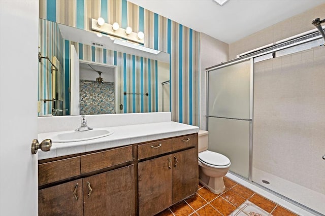 bathroom with tile patterned floors, toilet, vanity, and walk in shower