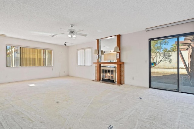 unfurnished living room with light colored carpet, a healthy amount of sunlight, and a textured ceiling