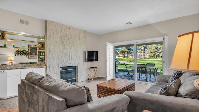 carpeted living room with a stone fireplace