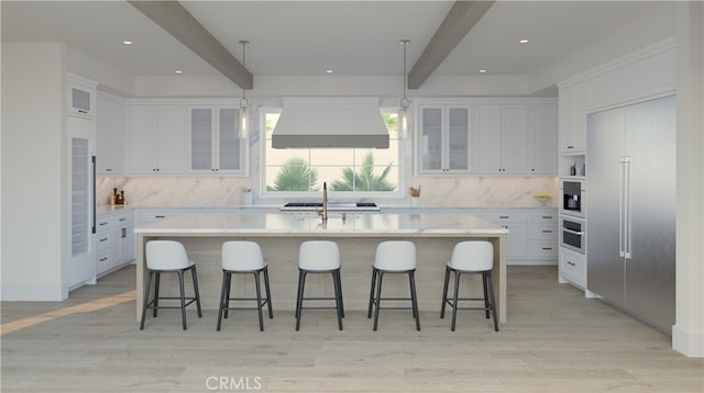 kitchen with ventilation hood, an island with sink, white cabinets, a kitchen breakfast bar, and beam ceiling