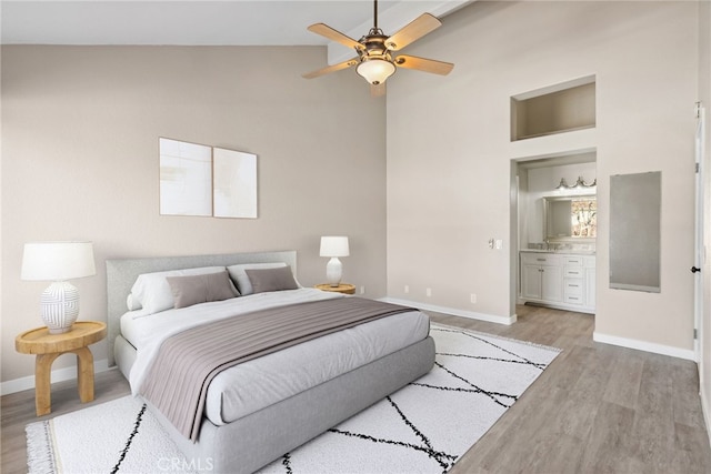 bedroom with light wood-type flooring, ensuite bathroom, vaulted ceiling, and ceiling fan