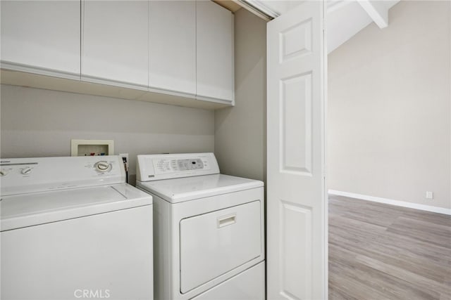 washroom featuring cabinets, light wood-type flooring, and washing machine and clothes dryer