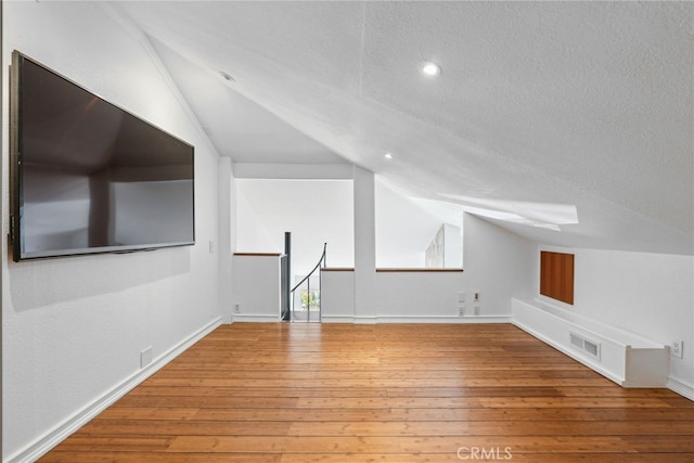 bonus room with a textured ceiling, hardwood / wood-style flooring, and vaulted ceiling