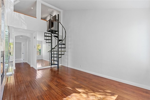 unfurnished living room with hardwood / wood-style floors and a towering ceiling