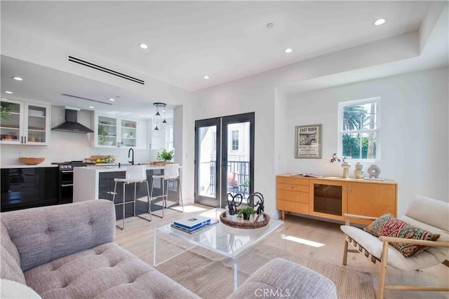 living room featuring french doors, light wood-type flooring, and sink