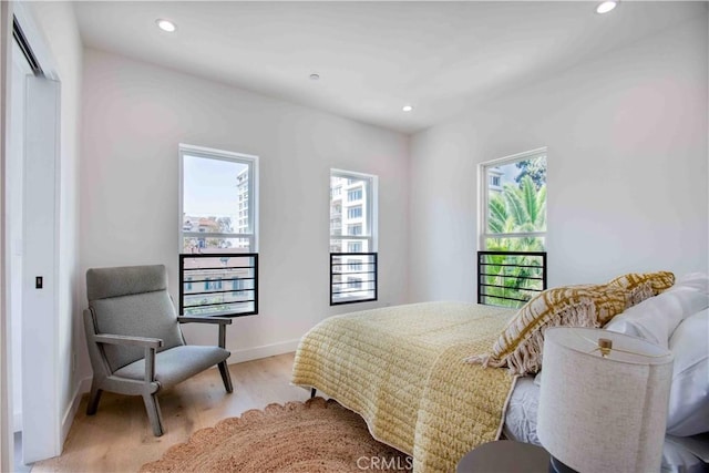 bedroom with a closet, light hardwood / wood-style flooring, and multiple windows