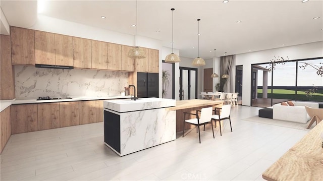 kitchen featuring black gas cooktop, backsplash, a center island with sink, and hanging light fixtures