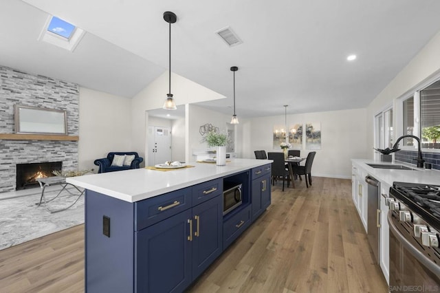 kitchen with blue cabinetry, a center island, light hardwood / wood-style floors, and sink