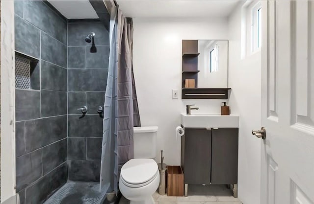 bathroom with toilet, marble finish floor, a tile shower, and vanity