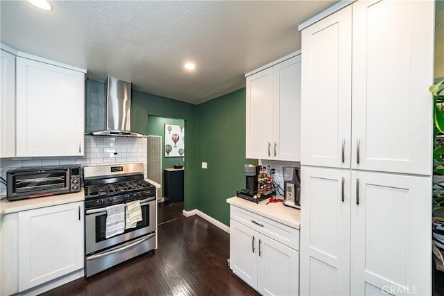 kitchen featuring wall chimney exhaust hood, a toaster, light countertops, and gas stove