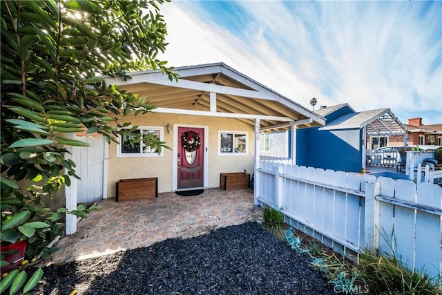 exterior space featuring a patio area, fence, and stucco siding