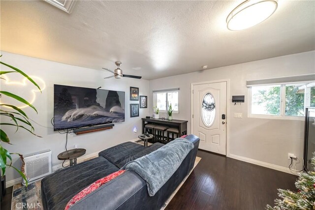 living room featuring ceiling fan, dark hardwood / wood-style flooring, and a textured ceiling