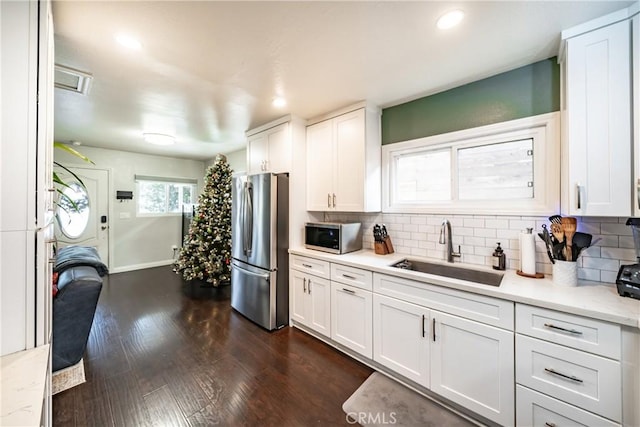 kitchen featuring stainless steel appliances, white cabinetry, a sink, and decorative backsplash