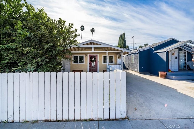 bungalow-style house with a fenced front yard and stucco siding