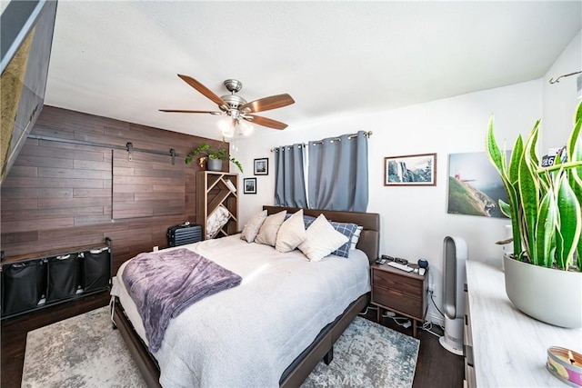 bedroom featuring wood finished floors, a ceiling fan, and wooden walls