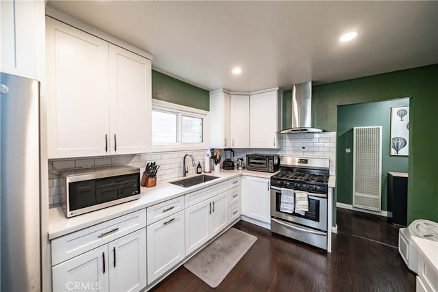 kitchen with white cabinets, wall chimney exhaust hood, sink, and appliances with stainless steel finishes