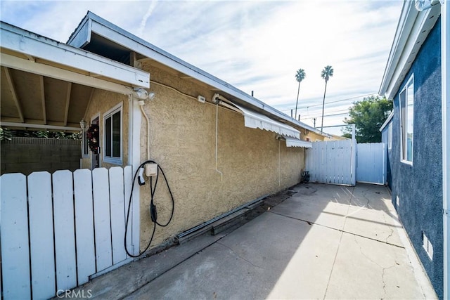 view of property exterior with a patio area, fence, and stucco siding