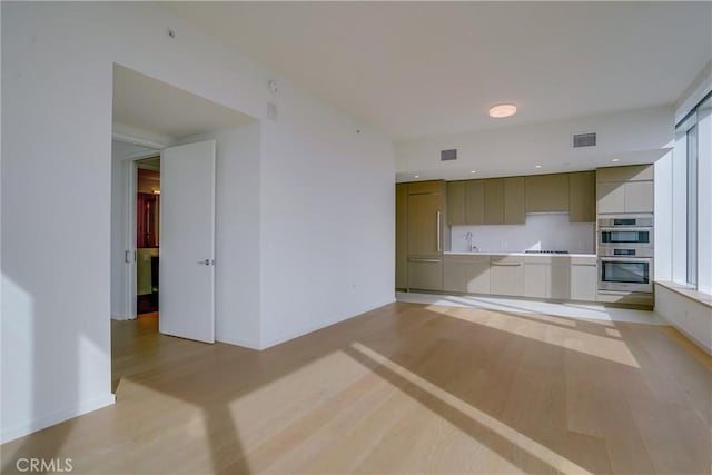 kitchen featuring black cooktop, sink, stainless steel double oven, and light wood-type flooring