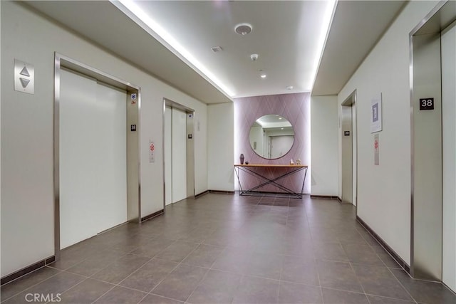 hallway with elevator and tile patterned floors