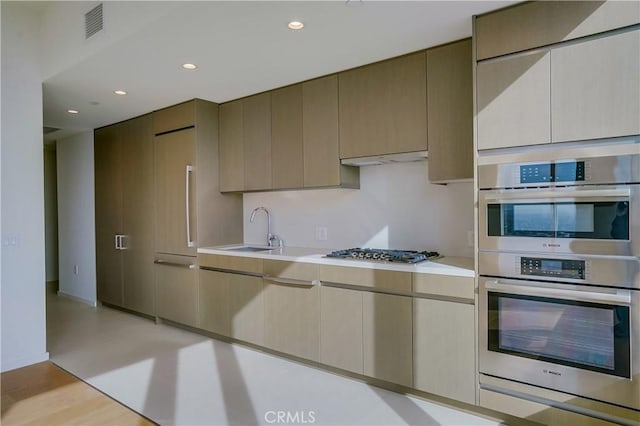 kitchen with sink, stainless steel appliances, and light hardwood / wood-style floors