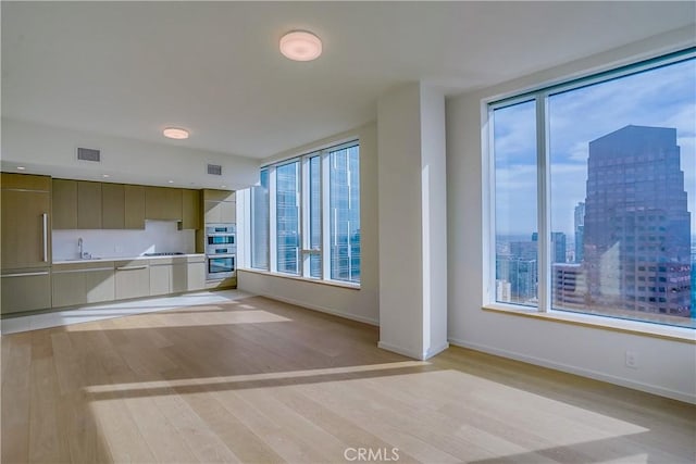 unfurnished living room featuring sink and light hardwood / wood-style flooring