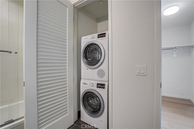 laundry area featuring stacked washer and dryer and light wood-type flooring