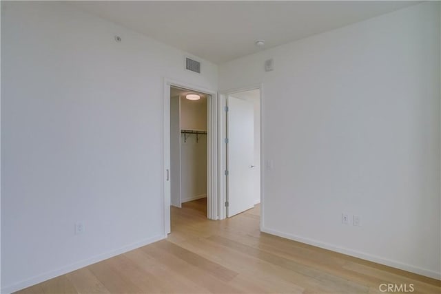 unfurnished bedroom with light hardwood / wood-style floors, a walk in closet, and a closet