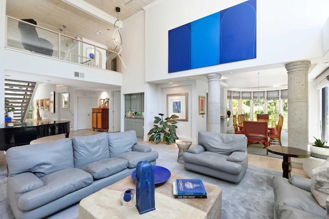 living room with hardwood / wood-style floors, a towering ceiling, and decorative columns