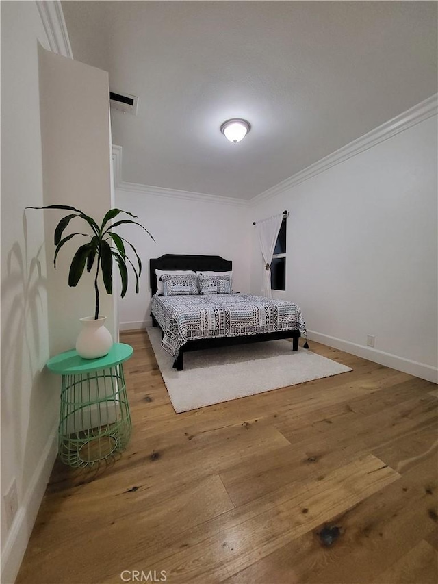 bedroom with hardwood / wood-style flooring and crown molding