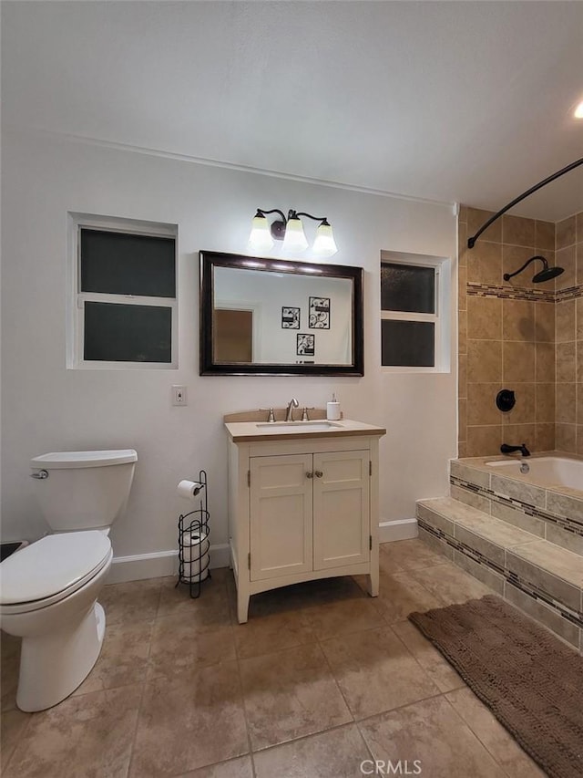 full bathroom featuring tile patterned flooring, tiled shower / bath combo, vanity, and toilet