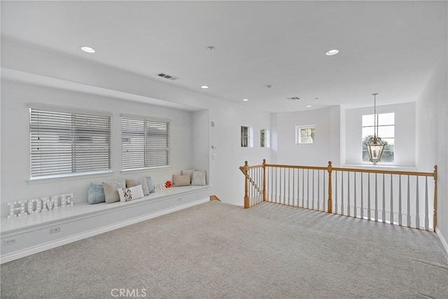 carpeted spare room featuring a chandelier