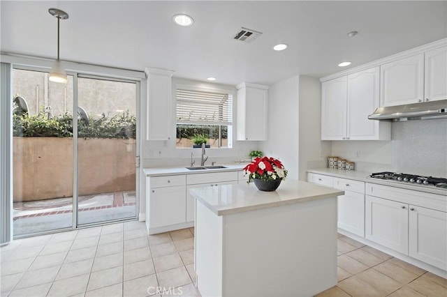 kitchen with pendant lighting, white cabinets, sink, light tile patterned flooring, and stainless steel gas cooktop