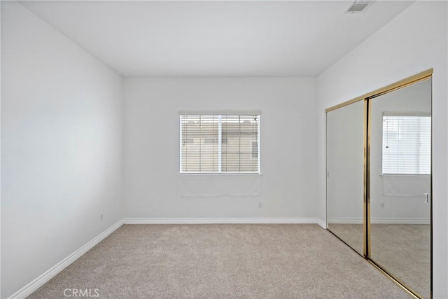 unfurnished bedroom featuring a closet and light colored carpet