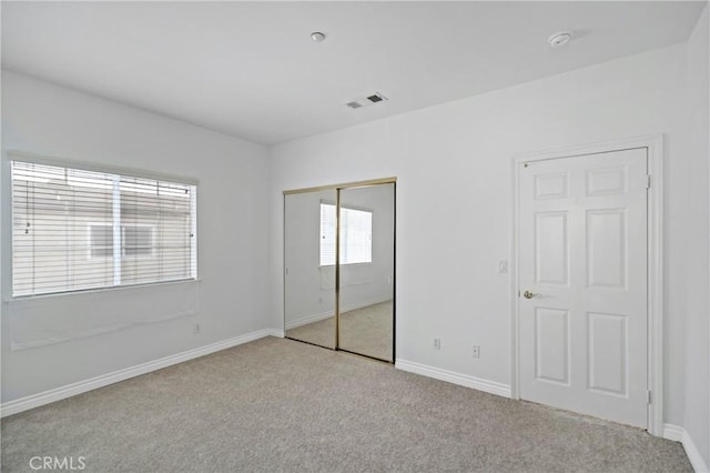 unfurnished bedroom featuring light carpet and a closet