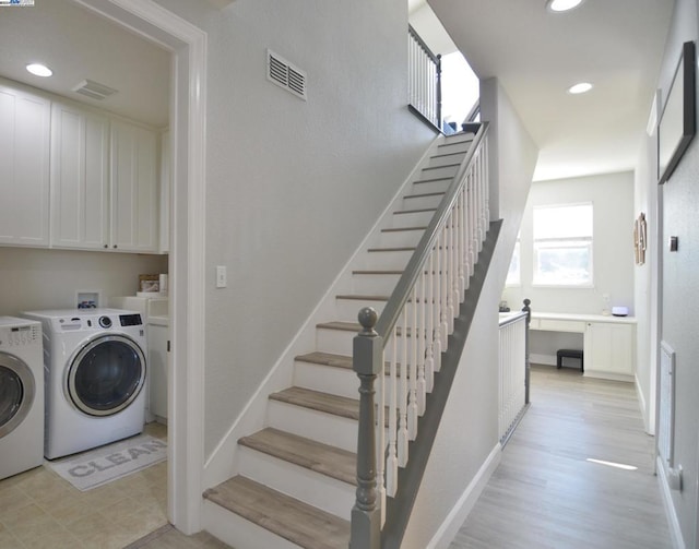 laundry room featuring cabinets, washer and dryer, and light hardwood / wood-style floors