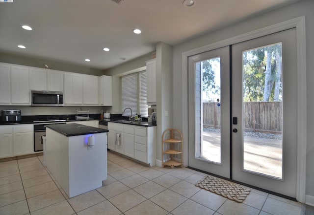 kitchen featuring white cabinetry, a center island, light tile patterned floors, and sink