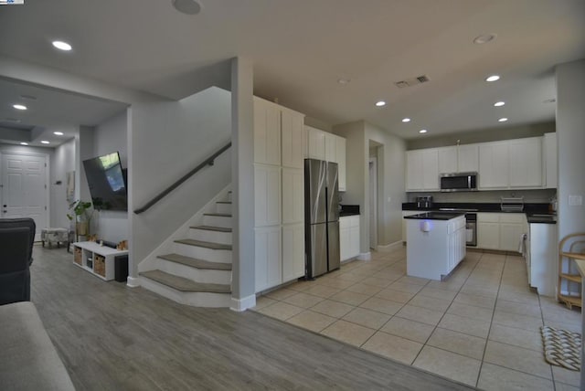 kitchen with white cabinets, a kitchen island, stainless steel appliances, and light hardwood / wood-style flooring