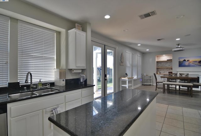 kitchen with dark stone counters, sink, white cabinets, light hardwood / wood-style floors, and a kitchen island