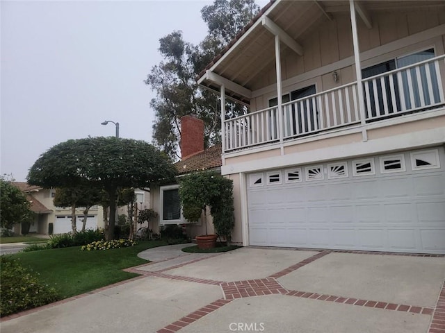 view of front of house featuring a front lawn, a garage, and a balcony