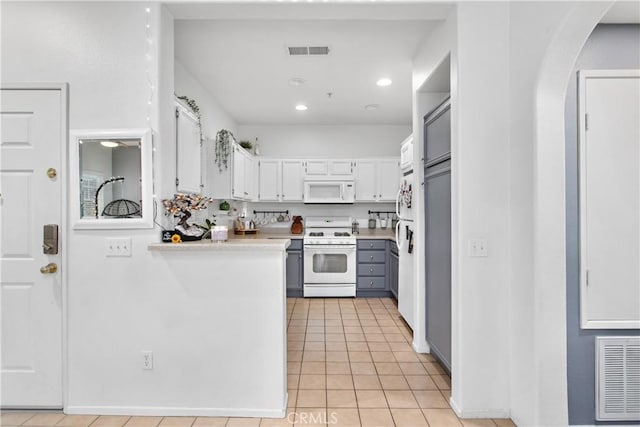 kitchen featuring white cabinets, light tile patterned floors, and white appliances