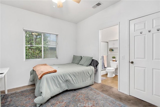 bedroom with ceiling fan, carpet floors, and ensuite bathroom