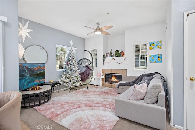 carpeted living room with ceiling fan and a tiled fireplace