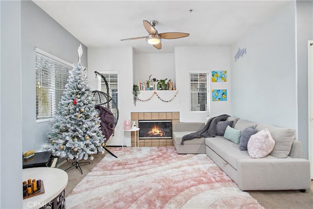 carpeted living room with ceiling fan and a tiled fireplace