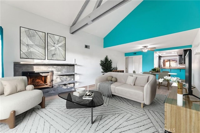 living room with a tile fireplace, ceiling fan, beamed ceiling, high vaulted ceiling, and hardwood / wood-style floors